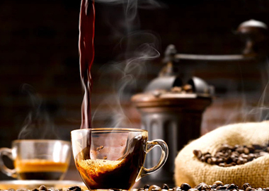 یک فنجان قهوه در کنار دانه های قهوه